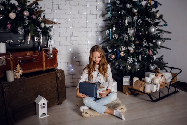 Bambini sotto l'albero di Natale con scatole regalo. Decorazioni di Capodanno. stile rustico, decorazioni in legno scuro interni di capodanno. sorelle.