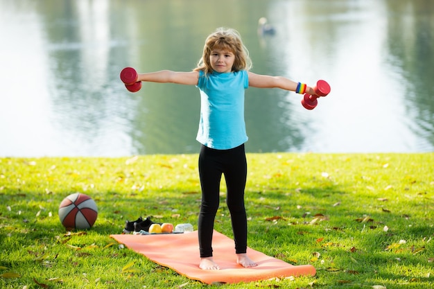 Bambini sport ragazzo sano con manubri esercizio all'aperto piccolo bambino pratica esercizi con manubri