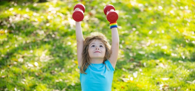 Bambini sportivi Bambini sportivi con muscoli bicipiti forti Bambini che esercitano manubri fitness Ragazzino forte che si esercita con manubri nel parco all'aperto