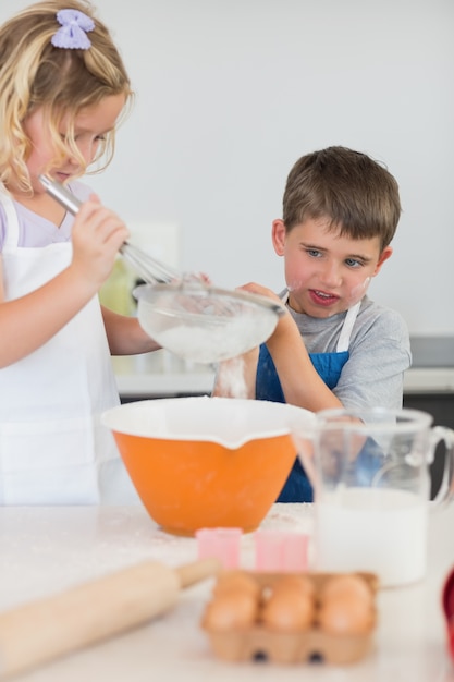 Bambini svegli che cuociono i biscotti in cucina