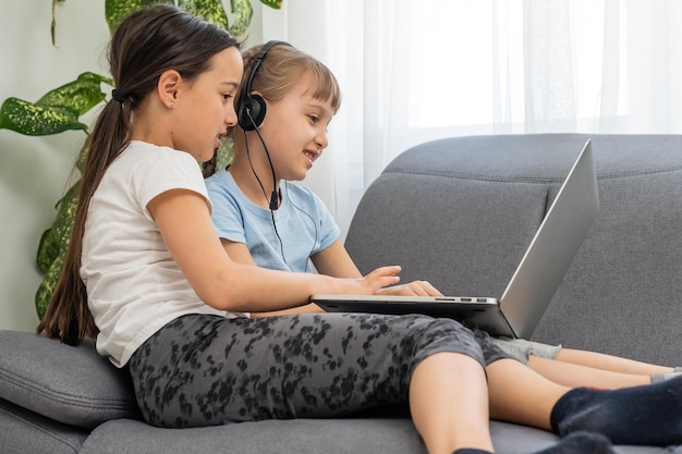 Bambini svegli che fanno i compiti con il computer portatile.