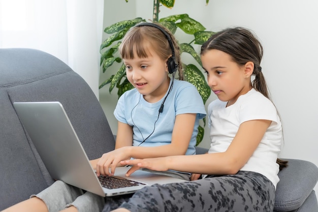 Bambini svegli che fanno i compiti con il computer portatile.