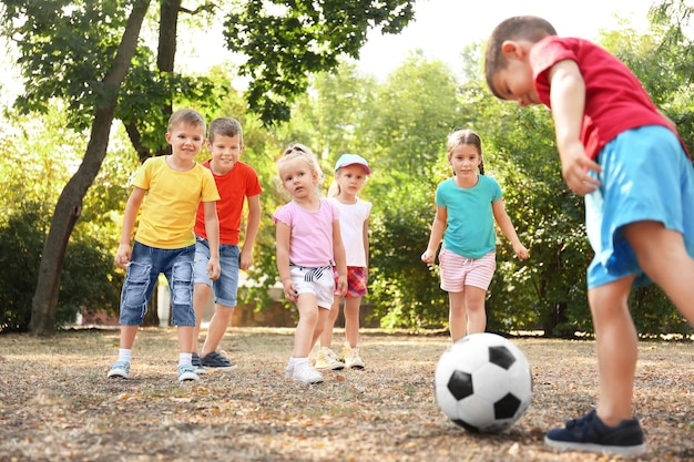 Bambini svegli che giocano con la palla nel parco