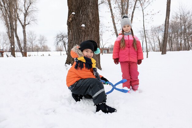 Bambini svegli che giocano nel parco innevato in vacanza invernale