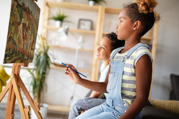 Bambini svegli ragazza e ragazzo che dipingono insieme. Concetto di educazione, arte, divertimento e creatività.