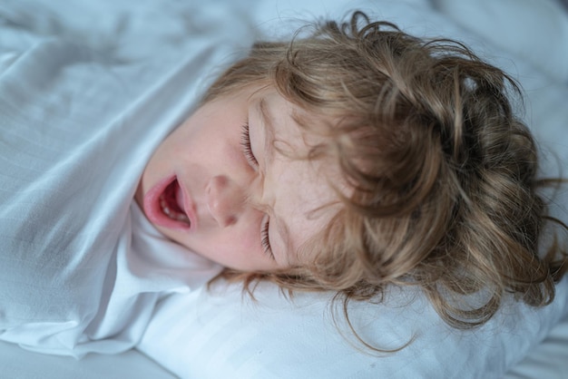 Bambini tranquilli sdraiati su un letto mentre dormono in una camera da letto luminosa Svegliati buongiorno