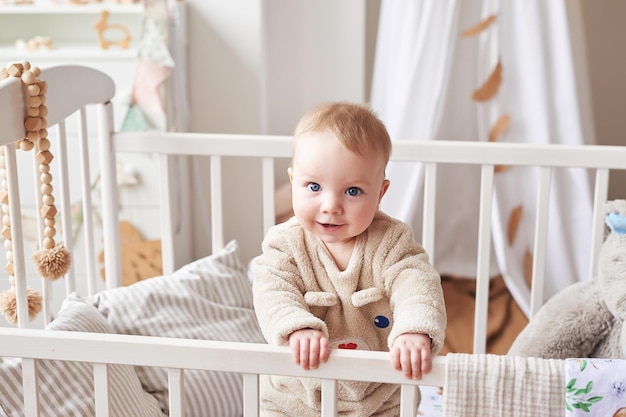 Bambino 6 mesi in piedi nella culla nella stanza dei bambini. Buona maternità e paternità. Ospedale e clinica di maternità. Festa del papà e della mamma. Sviluppo della prima infanzia, asilo nido