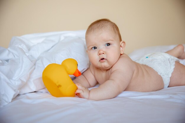 bambino a casa in camera da letto sdraiato su un lenzuolo bianco avvolto in un asciugamano dopo il bagno