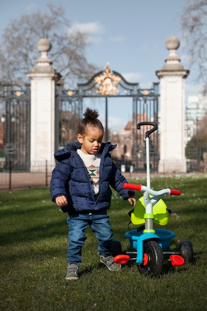 Bambino a tutto campo con triciclo nel parco