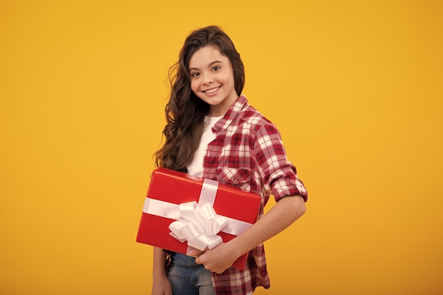 Bambino adolescente in camicia con scatola regalo su sfondo giallo isolato Regalo per il compleanno dei bambini Adolescente felice emozioni positive e sorridenti della ragazza adolescente