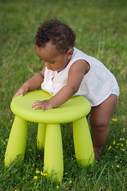 Bambino adorabile che gioca con una sedia nel giardino