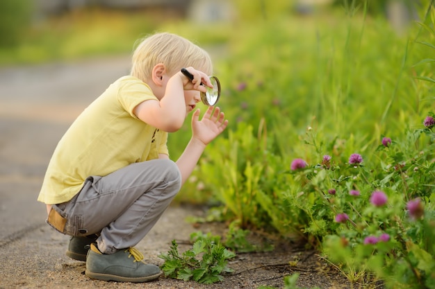 Bambino affascinante che esplora la natura con la lente d&#39;ingrandimento