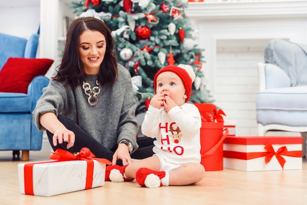 Bambino affascinante con sua madre che disimballa il regalo di feste.