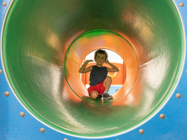 Bambino all'ingresso di un tubo in un gioco del parco giochi