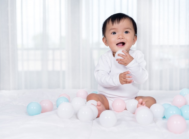 Bambino allegro che gioca la palla di colore sul letto