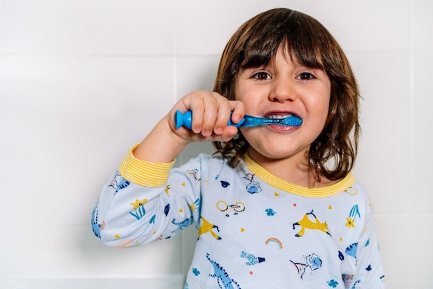 Bambino allegro che si lava i denti in pigiama prima di coricarsi
