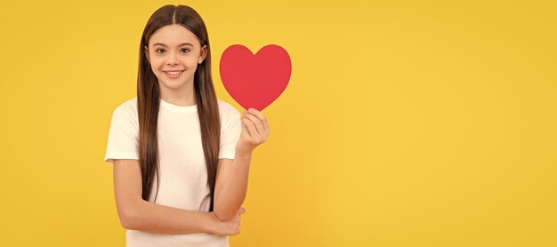 Bambino allegro con cuore rosso su sfondo giallo giorno dell'amore Ritratto di ragazza bambino con poster orizzontale simbolo di amore del cuore Intestazione banner con spazio di copia