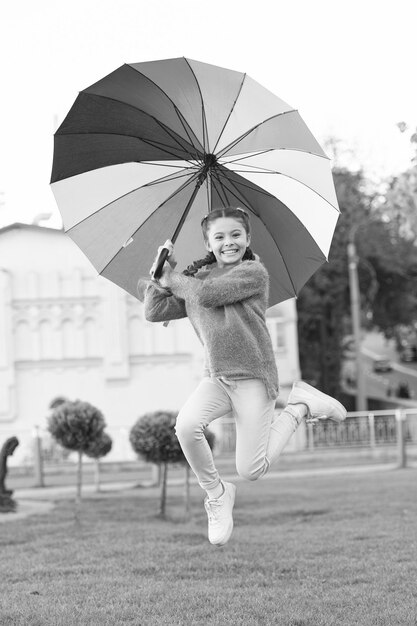 Bambino allegro felice e libero Stile primaverile Arcobaleno dopo la pioggia Bambina sotto l'ombrello colorato Umore positivo in autunno Ombrello multicolore per bambina felice Sentirsi felici