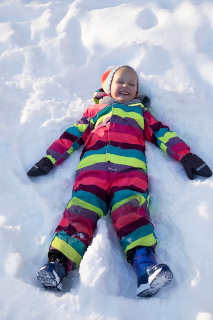 Bambino allegro sdraiato sulla neve