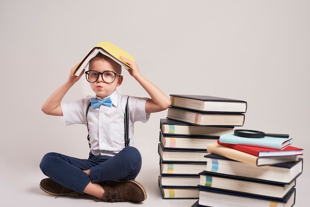 Bambino annoiato con una pila di libri