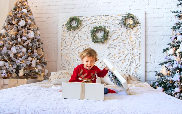 Bambino aperto regali di Natale sotto l'albero Messa a fuoco selettiva