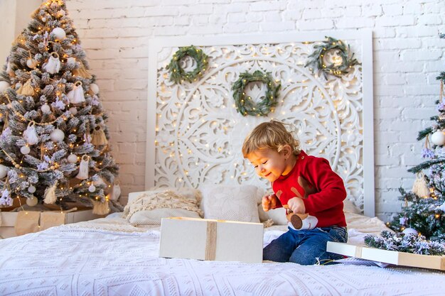 Bambino aperto regali di Natale sotto l'albero Messa a fuoco selettiva