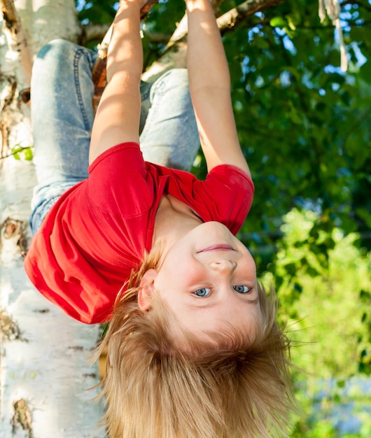 Bambino appeso a un ramo d'albero