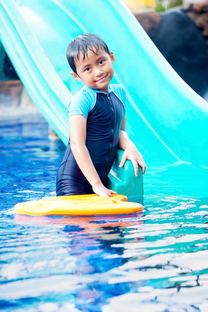 Bambino asiatico carino che posa in piscina