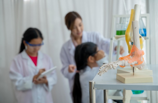 Bambino asiatico che impara con lo scienziato in laboratorio. Esame fisico e classe di educazione scientifica.