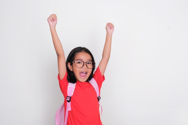 Bambino asiatico che indossa la borsa della scuola alzando le mani mostrando felicità