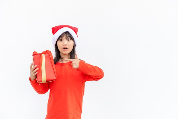 Bambino asiatico felice in cappello rosso della Santa che tiene i regali di Natale. Natale time.on sfondo bianco.