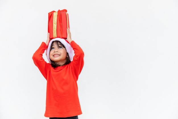 Bambino asiatico felice in cappello rosso della Santa che tiene i regali di Natale. Natale time.on sfondo bianco.