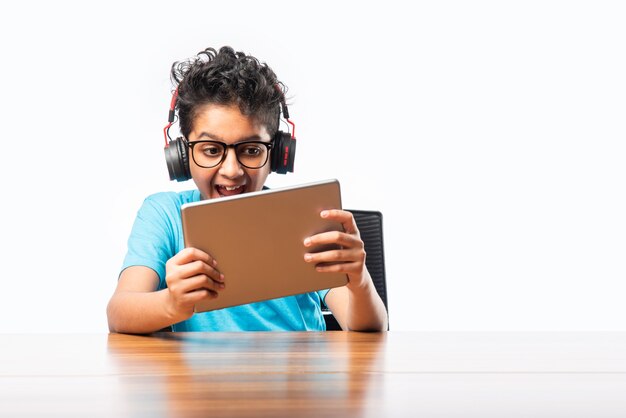 Bambino asiatico indiano che gioca o studia su tablet, wireless