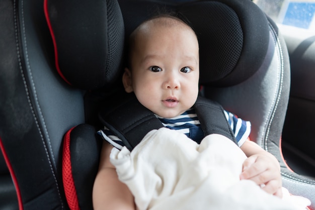 Bambino asiatico nel seggiolino auto