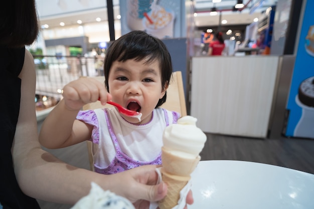 Bambino asiatico sveglio che mangia il gelato nel ristorante