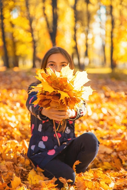 Bambino autunnale nel parco con foglie gialle Messa a fuoco selettiva Kid