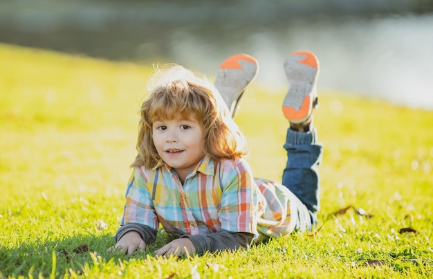 Bambino bambino all'aperto nel parco primavera ragazzo sdraiato sull'erba passeggiata estiva adattamento dei bambini