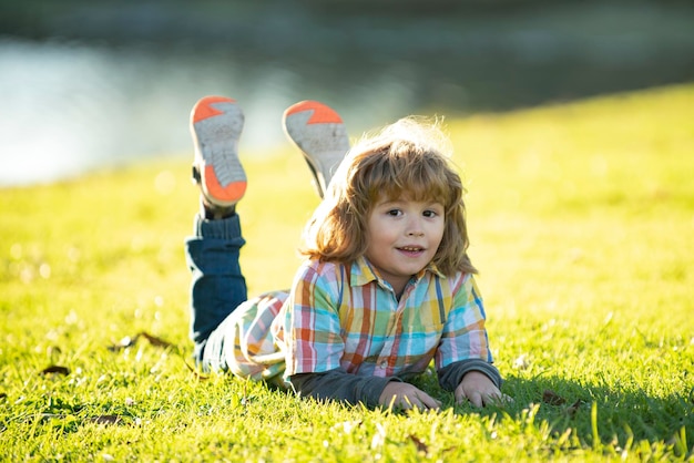 Bambino bambino all'aperto nel parco primavera ragazzo sdraiato sull'erba passeggiata estiva adattamento dei bambini