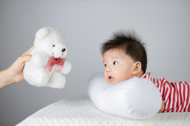 Bambino Bambino che guarda Mano che tiene l'orsacchiotto sopra il bambino.