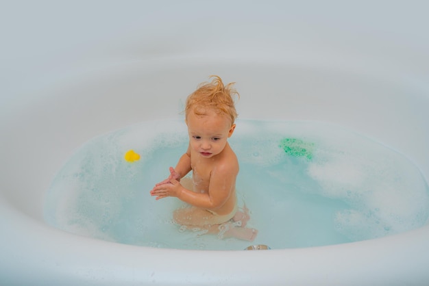 Bambino bambino fare il bagno nella vasca da bagno bianca bambino adorabile che gioca con la schiuma