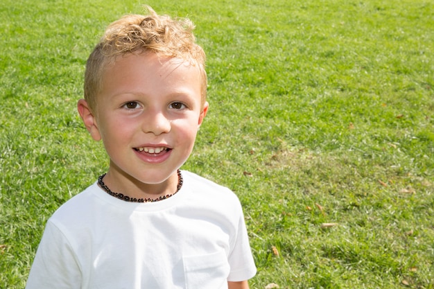 Bambino biondo felice sul bello campo di erba giallo verde