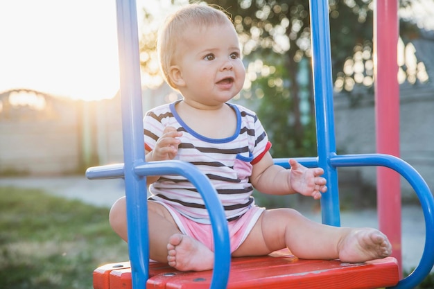 Bambino biondo seduto su un'altalena al tramonto