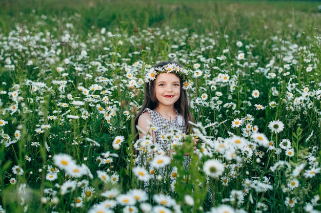 Bambino carino bambino in un campo di margherite al tramonto. Tonificante