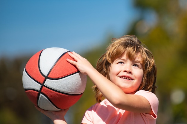 Bambino carino che gioca a basket Ragazzo sorridente carino gioca a basket Bambini attivi che si divertono con il gioco all'aperto