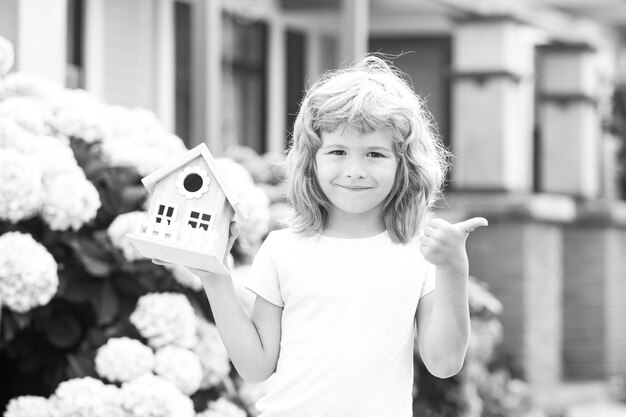 Bambino carino che gioca con il modello di piccola casa all'aperto a casa giardino ecologico casa nelle mani dei bambini aga