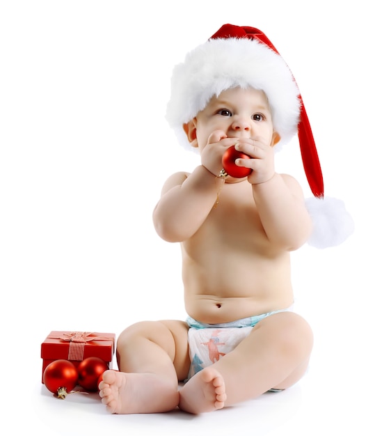 Bambino carino con cappello di Babbo Natale e decorazioni natalizie isolate su superficie bianca