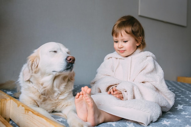 Bambino carino e il suo labrador retriever a casa sul letto