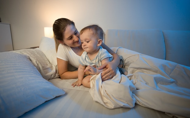 Bambino carino e sua madre a letto a tarda notte