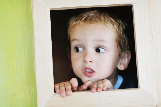 bambino carino felice in una finestra di legno al parco giochi