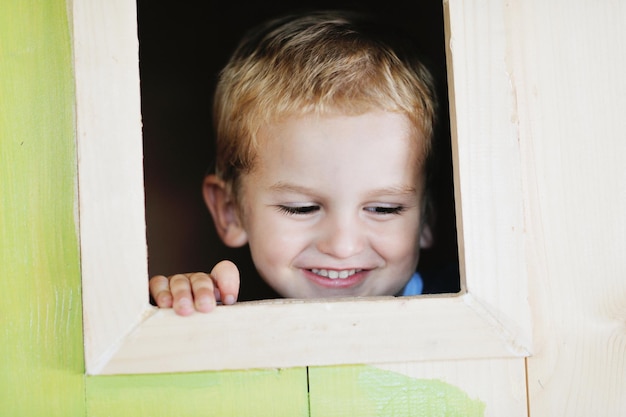 bambino carino felice in una finestra di legno al parco giochi